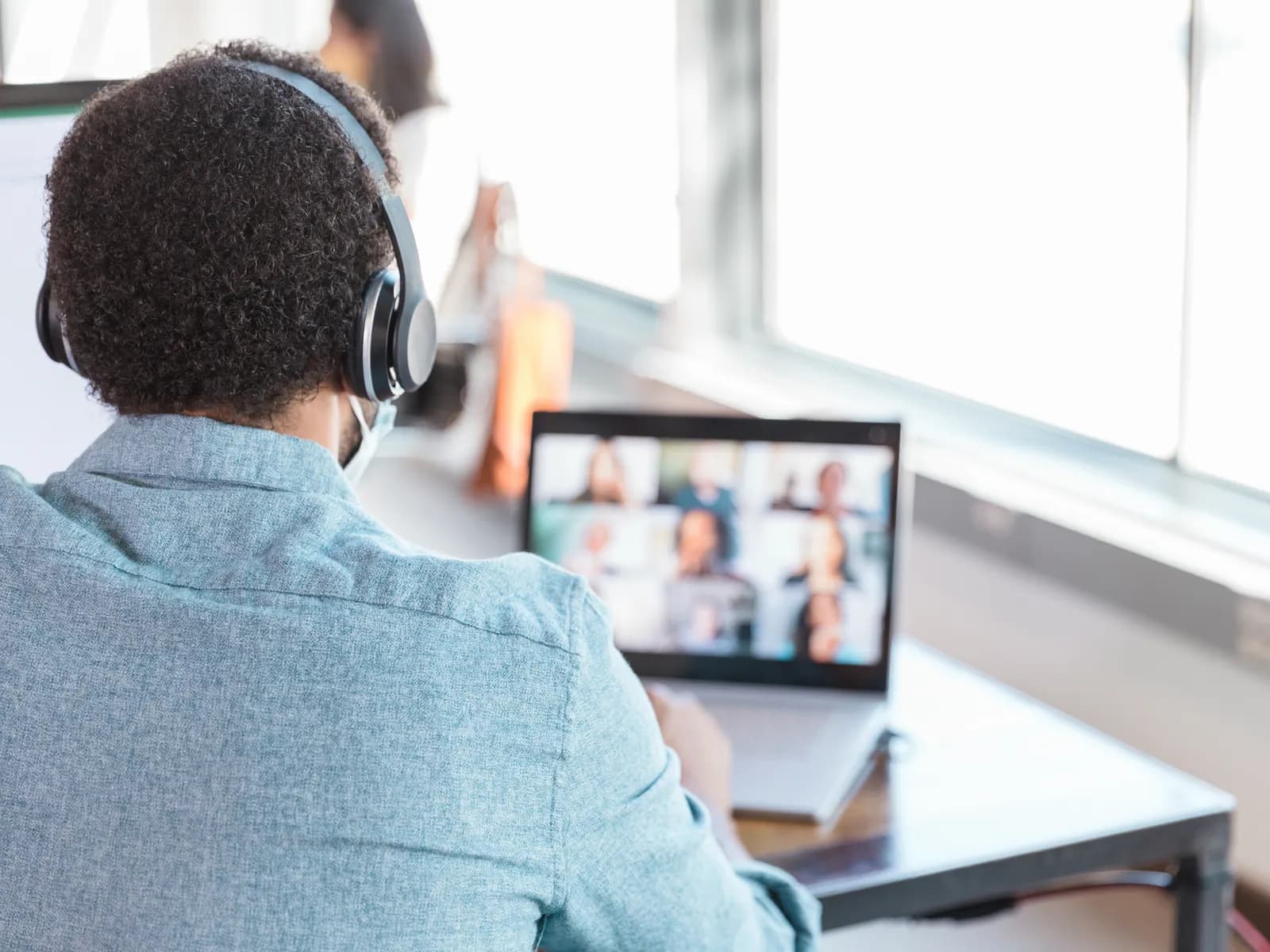 Teilnehmer mit Headset folgt einem Deutschkurs per Videounterricht am Laptop