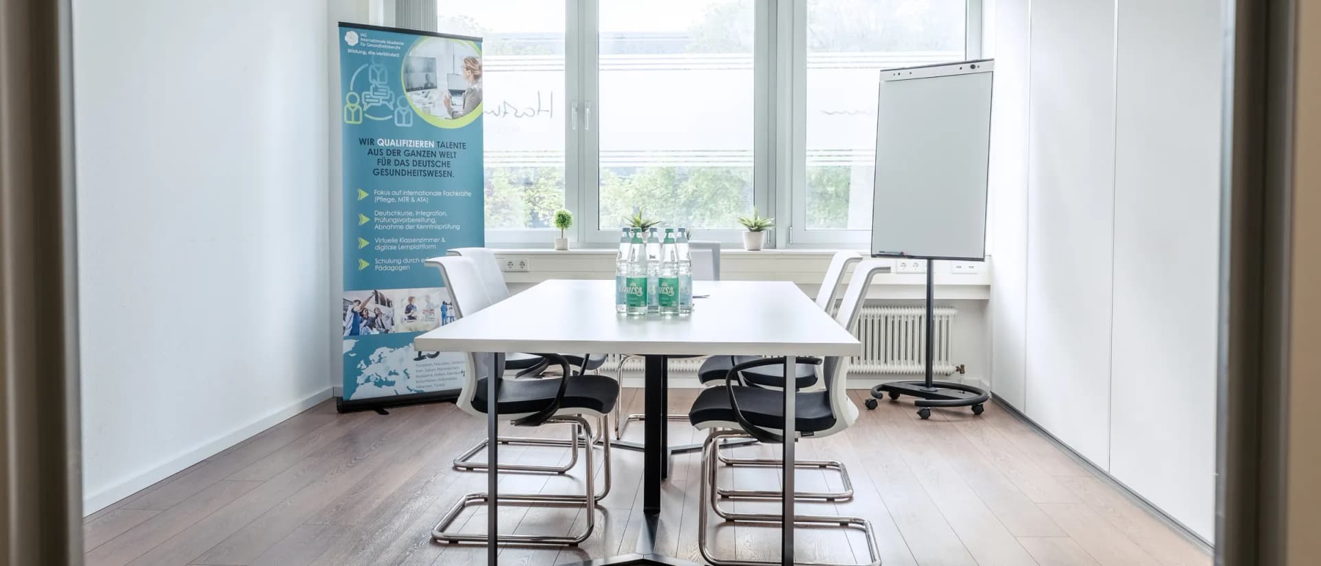 Seminarraum mit Tisch, Flipchart und IAG-Roll-up